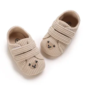 Vue détaillée de chaussures bébé en velours côtelé beige avec un motif d'ours brodé
