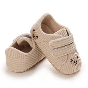 Gros plan sur des chaussures de bébé en velours beige avec broderie ours et brides