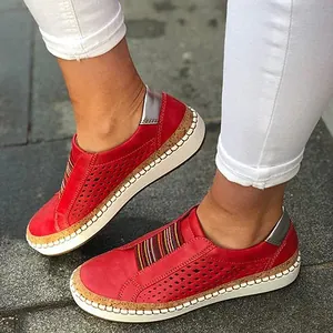 Primo piano di mocassini in pelle rossa traforata con strisce colorate e sughero