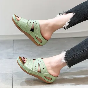 Détail de sandales à talons compensés vert clair avec broderie laser et semelle épaisse.