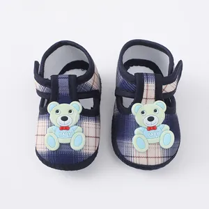 Detailopname van babyschoenen met zachte zool, ruitpatroon en schattige beerdecoratie