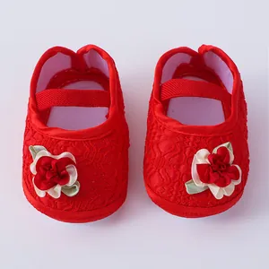 Nahaufnahme von roten Baby-Prinzessin-Schuhen aus Spitze mit Stoffblumen-Details