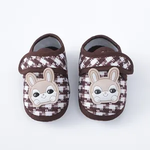 Detail van baby loopschoentjes met een schattig konijntje en een klassiek ruitpatroon