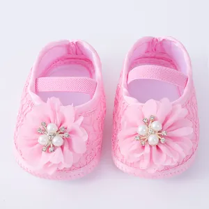 Detailed shot of pink lace baby princess shoes with chiffon flower and pearl accent.