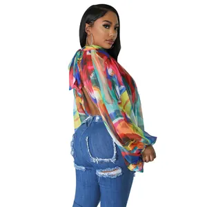 Vista posteriore di una donna con camicetta in chiffon a stampa astratta e jeans strappati.