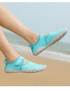 Close-up view of mint green breathable mesh aqua shoes for women on a sunny sandy beach