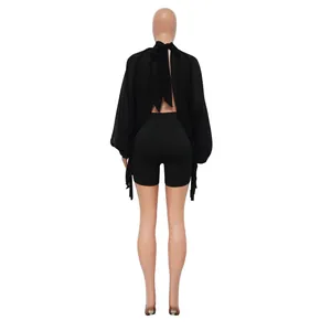 Vista posteriore di un top in chiffon nero con laccetti e pantaloncini aderenti