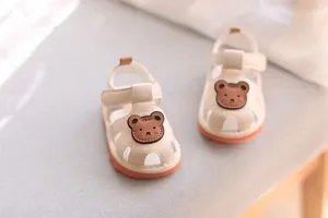 Close-up of beige baby walking sandals with cute cartoon bear and soft non-slip sole