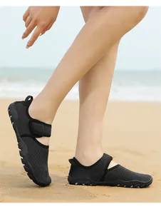 Detailed side view of breathable black mesh water shoes worn on a sandy beach