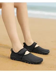 Close-up of breathable black water shoes worn on a sandy beach setting for outdoor sports.