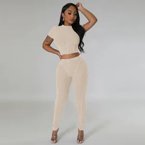 Full body view of a woman wearing a beige ribbed knit two-piece crop top and leggings set