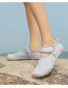 Detailed view of grey breathable mesh water shoes for swimming worn on rocky beach terrain