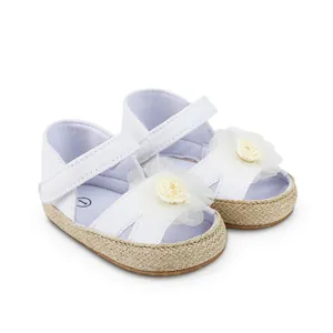 Vista detallada de zapatos de princesa para bebé blancos con suela tejida y flor