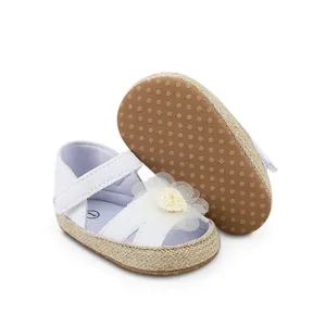 Detalle de zapatos de princesa para bebé blancos con flor y suela antideslizante