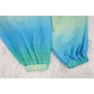 Dettaglio dei polsini elastici di un top in chiffon con sfumatura blu-verde.