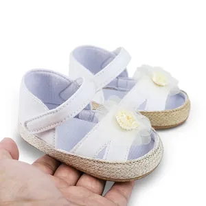 Detalle de zapatos blancos de princesa para bebé con suela blanda y adorno de flor.
