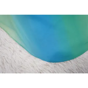 Dettaglio dell'orlo di una camicetta in chiffon sfumato verde-blu con cuciture di qualità