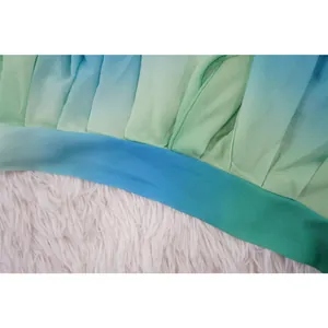 Dettaglio macro della trama del tessuto in chiffon plissettato con sfumatura blu e verde.
