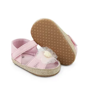 Primer plano de zapatos rosa para bebé con suela antideslizante y detalle floral.