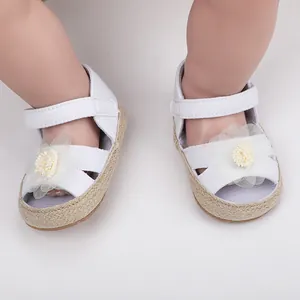 Nahaufnahme weißer Baby-Sandalen für Mädchen mit zarter Blume und weicher Flechtsohle