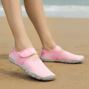 Women's pink breathable water shoes with anti-slip rubber sole on a sandy beach