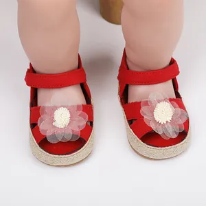 Detalle de zapatos de princesa rojos para bebé con decoración de flor blanca y suela blanda