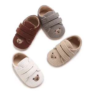 Vue détaillée de chaussures pour bébé en velours côtelé avec broderie d'ours en quatre couleurs.