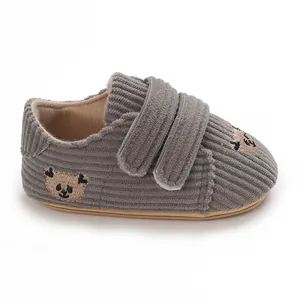 Détail de chaussures bébé en velours gris avec broderie panda et bandes velcro