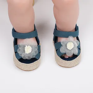 Primer plano de zapatos de bebé azul marino con detalle de flor blanca en los pies.