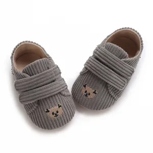 Détail de chaussures bébé en velours côtelé gris avec broderie ours