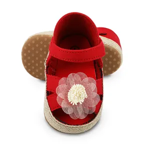 Nahaufnahme von roten Baby-Prinzessin-Schuhen mit weißer Blume und weicher Sohle.