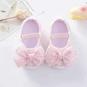 Close-up of pink baby princess shoes with decorative rhinestone bows and soft soles