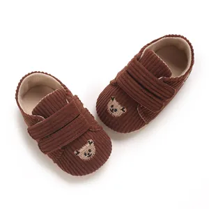 Vue détaillée de chaussures bébé en velours côtelé marron avec un motif d'ours brodé