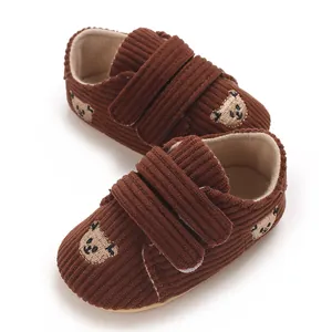 Vue détaillée de chaussures pour bébé en velours marron avec d'adorables ours brodés.