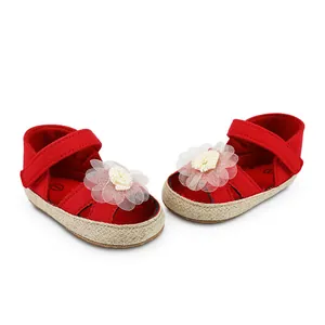 Detailansicht rote Baby-Mädchen-Lauflernschuhe mit weißer Stoffblumen-Dekoration.