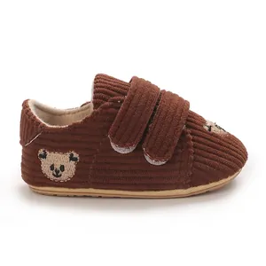 Vue détaillée d'un chausson bébé en velours marron avec broderie ours et scratchs