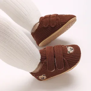 Gros plan sur chaussures bébé en velours côtelé marron avec broderie ours