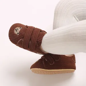 Détail de chaussures pour bébé en velours côtelé marron avec broderie ours mignonne