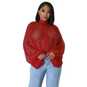 Dettaglio della camicetta in chiffon rosso trasparente con maniche a lanterna e collo alto.