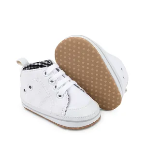 Close-up van witte baby canvas schoenen met antislip rubberen zolen met stippen.