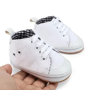 Detailopname van een witte baby loopschoen met geruite voering vastgehouden in hand