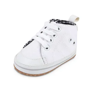 Detailopname van een witte canvas babyloopschoen met geruite voering en veters.