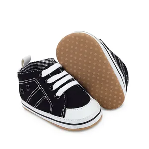 Gedetailleerd overzicht van baby-wandelschoenen in zwart en wit met antislip rubberen zool