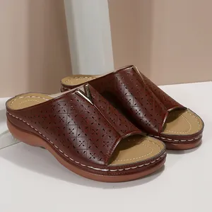 Detailansicht brauner Keilsandalen mit lasergeschnittenem Muster und Metall-V-Schnalle