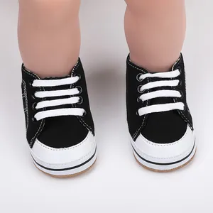 Detailopname van zwarte canvas babyschoentjes voor de eerste stapjes met witte veters.