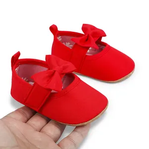 Primer plano detallado de zapatos de princesa rojos para bebé con suela blanda y lazos decorativos