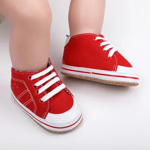 Detailopname van rode canvas baby loopschoentjes met witte veters en neus