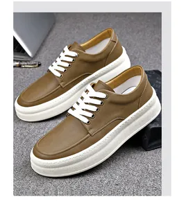 Close-up of men's brown leather thick-sole casual sneakers with white laces on grey surface.