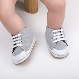 Gedetailleerde close-up van grijze baby-loopschoenen gedragen op een schone witte achtergrond.