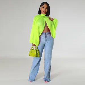 Modella che indossa un top in chiffon verde neon con maniche a pipistrello e jeans